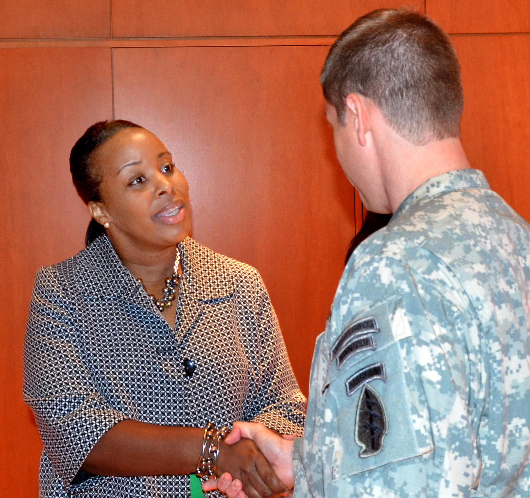Woman talking to soldier and shaking hands.