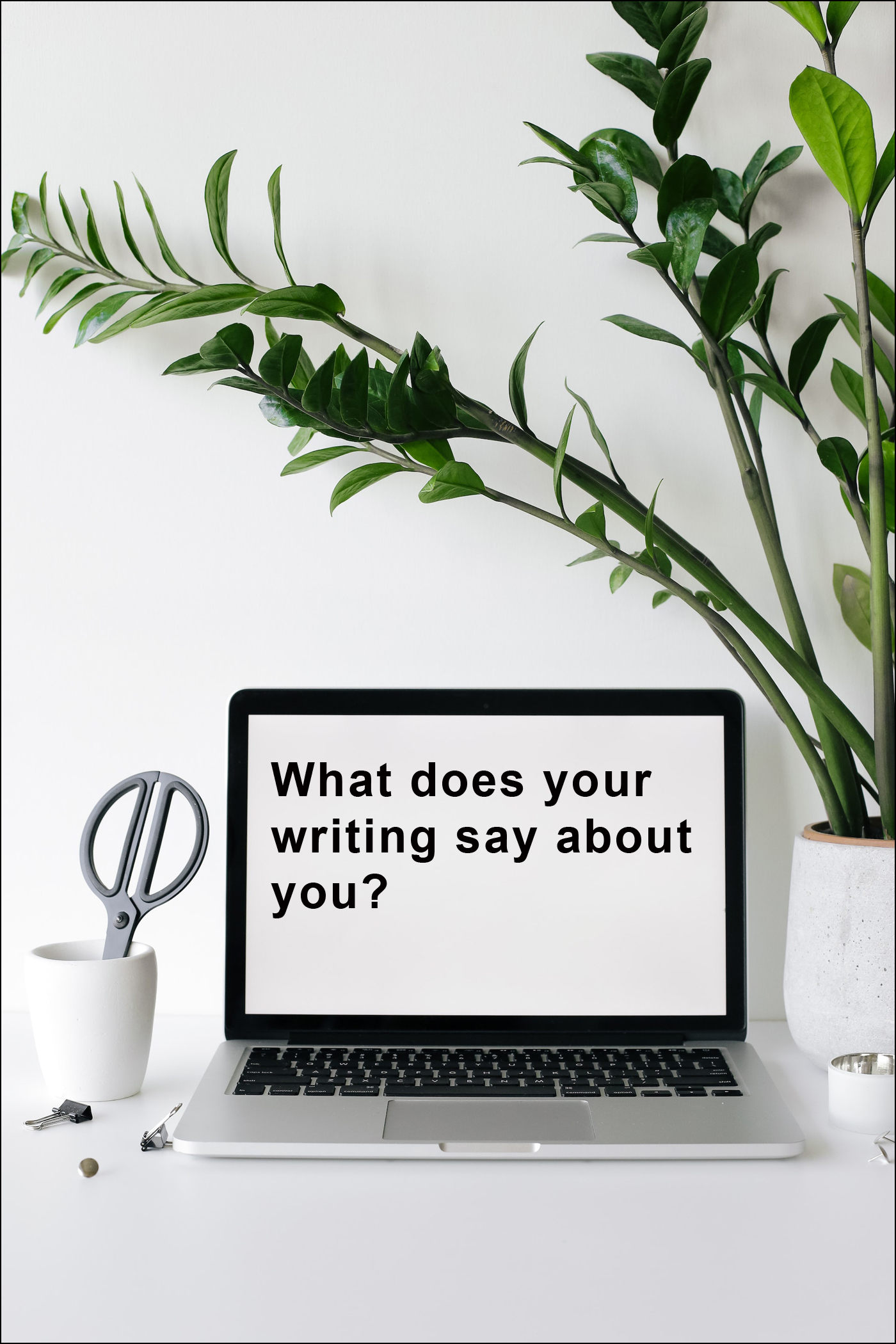 Laptop computer on desk with plant. Screen reads "What does your writing say about you?"